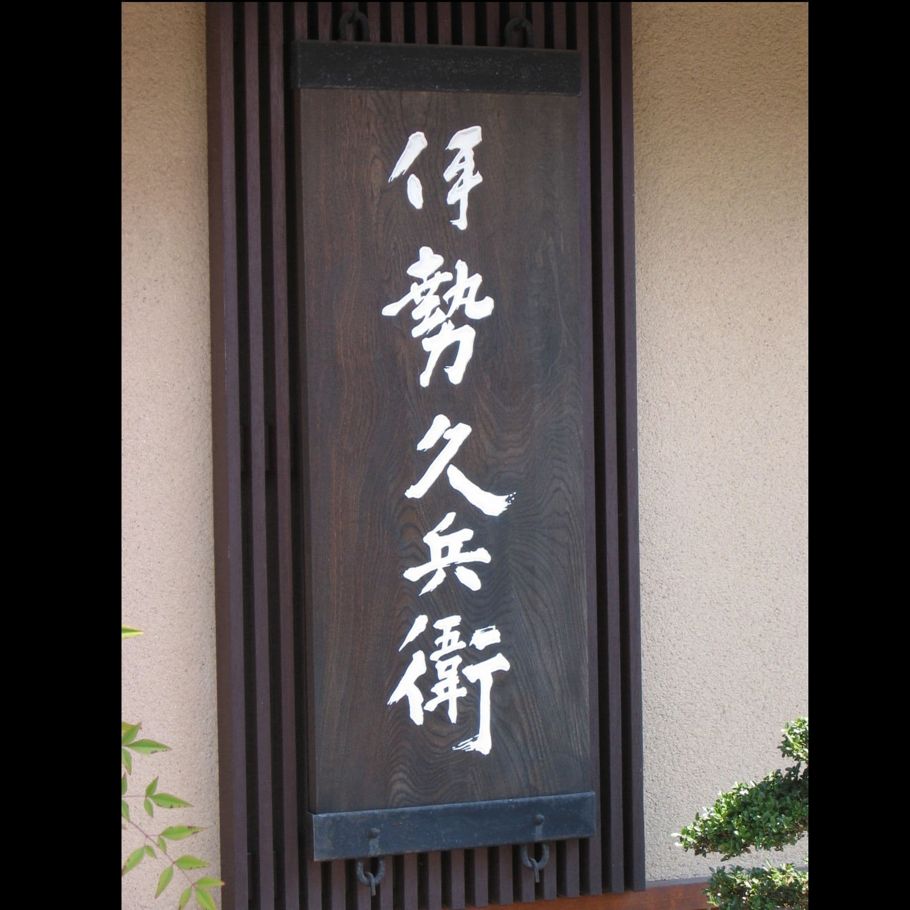 濃い色の木の板に白い文字が映える和風なイメージの看板