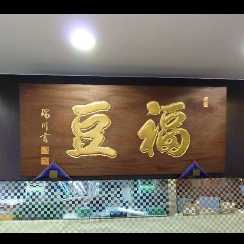 和菓子店の店内の壁面看板に木製看板、文字は彫刻して金色