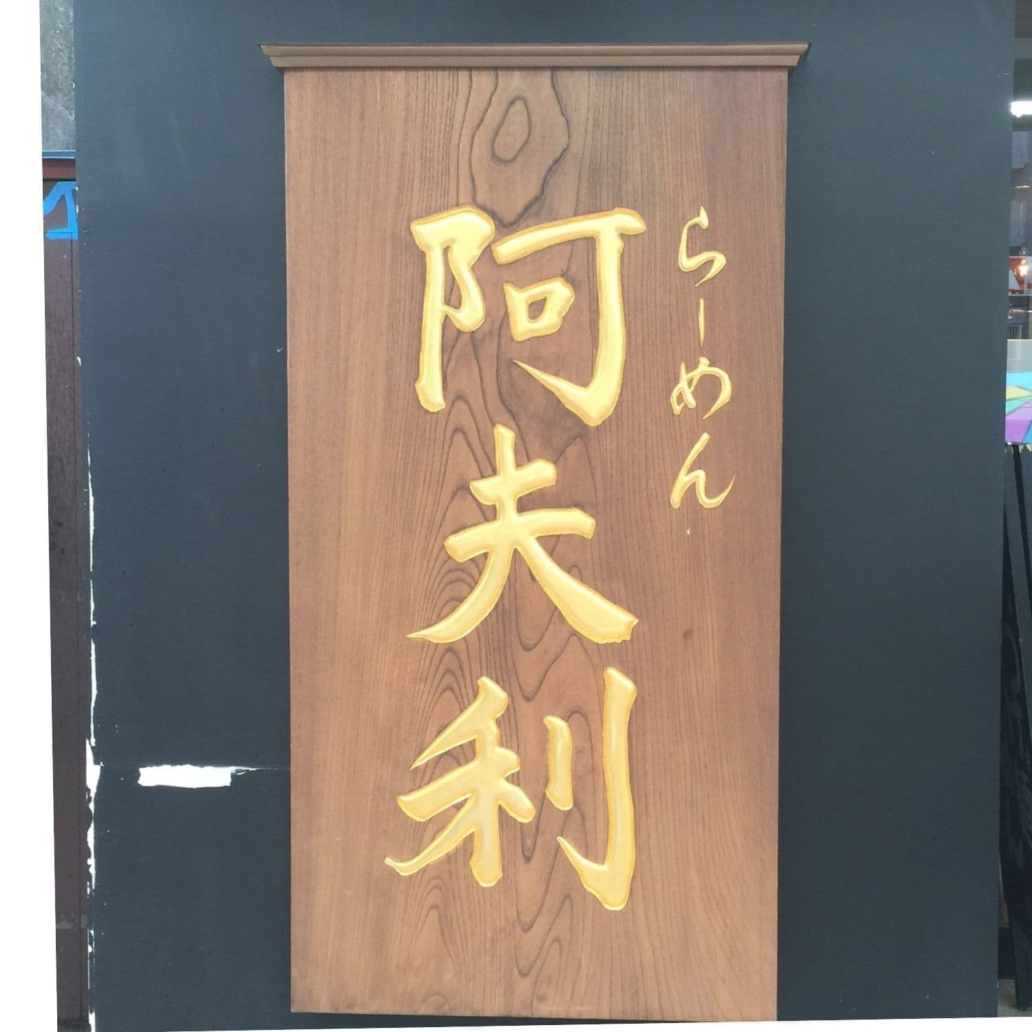 ラーメン店の入り口にケヤキの板に文字を彫刻して金箔で仕上げた看板