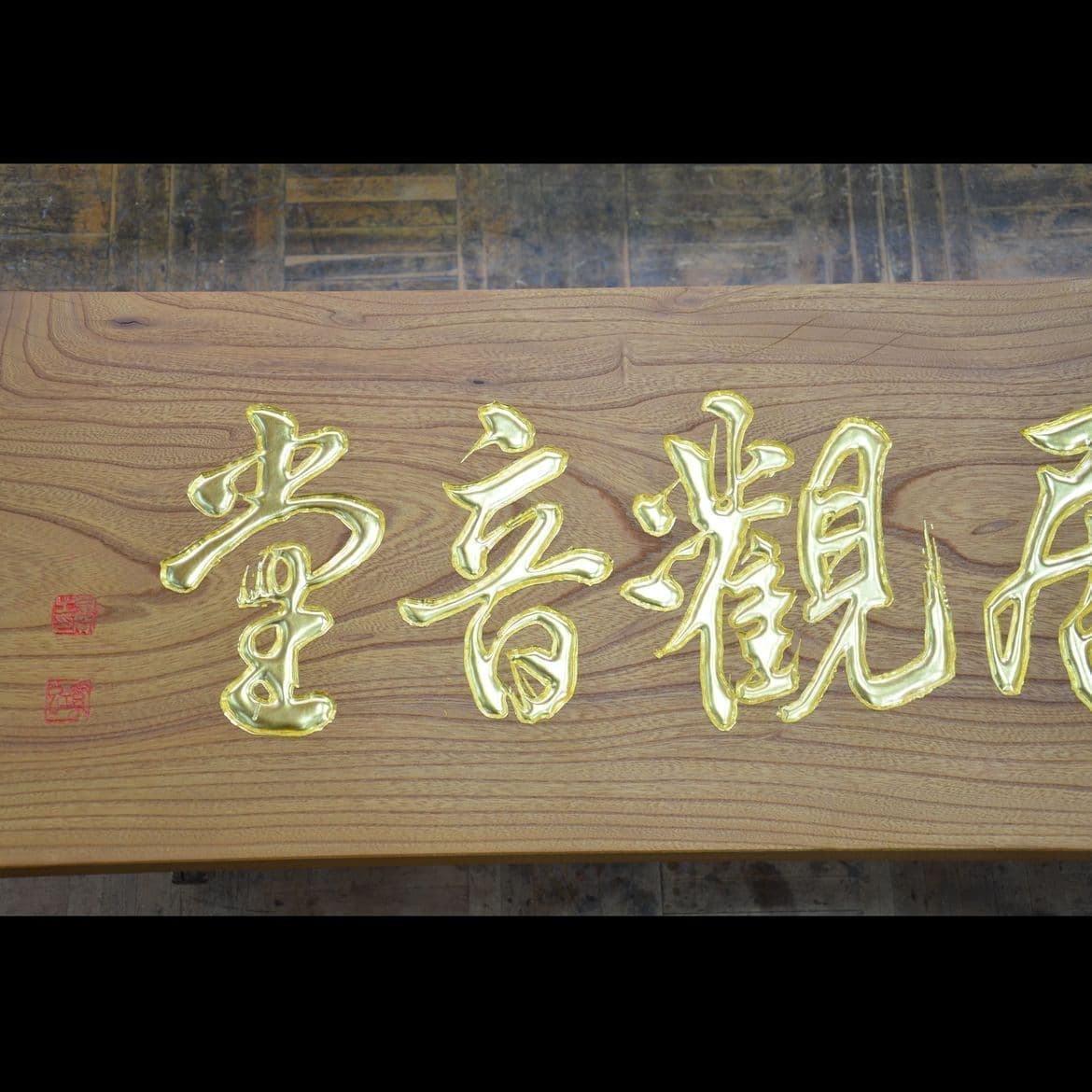 木の板に金色の彫刻でお寺の名前の看板、扁額