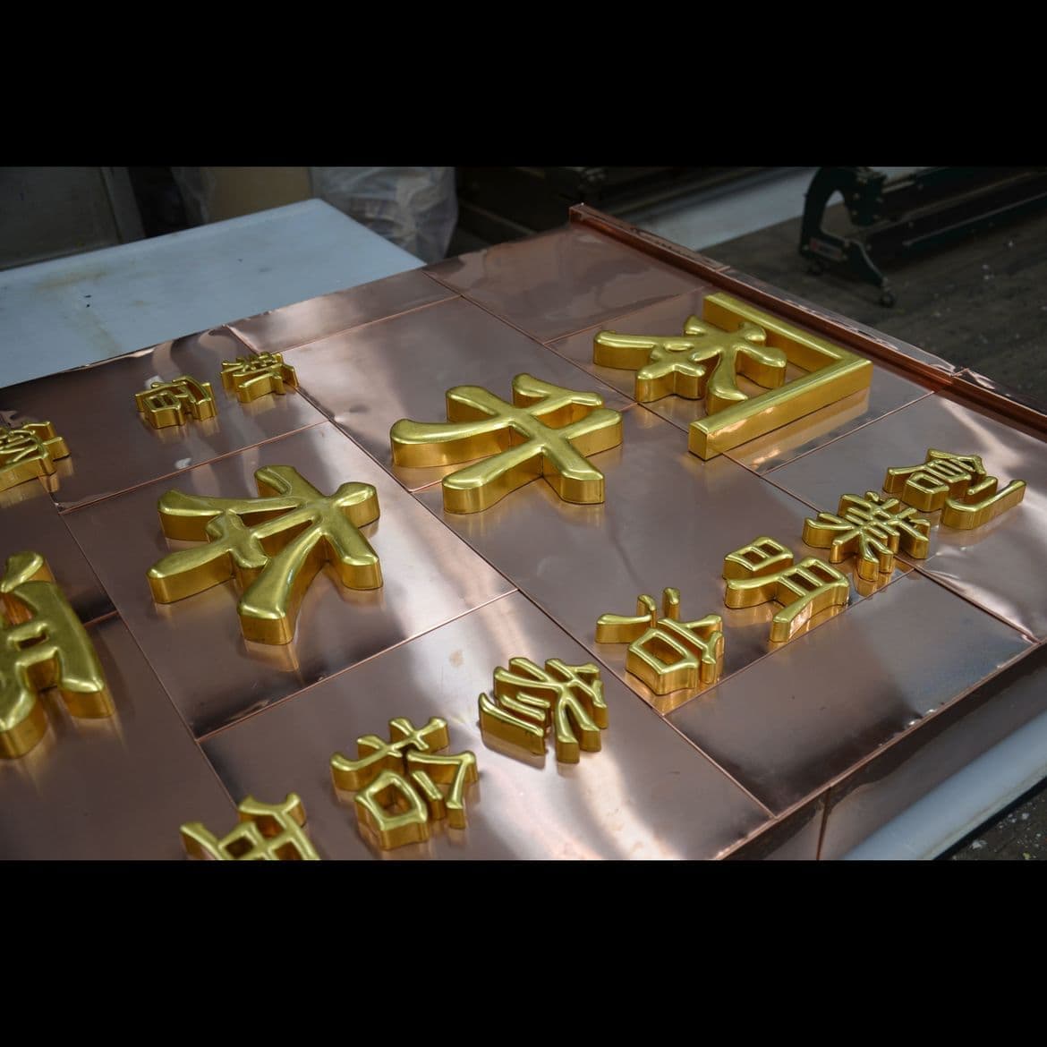 銅板金の台に立体の金文字の酒屋さんの看板の制作風景