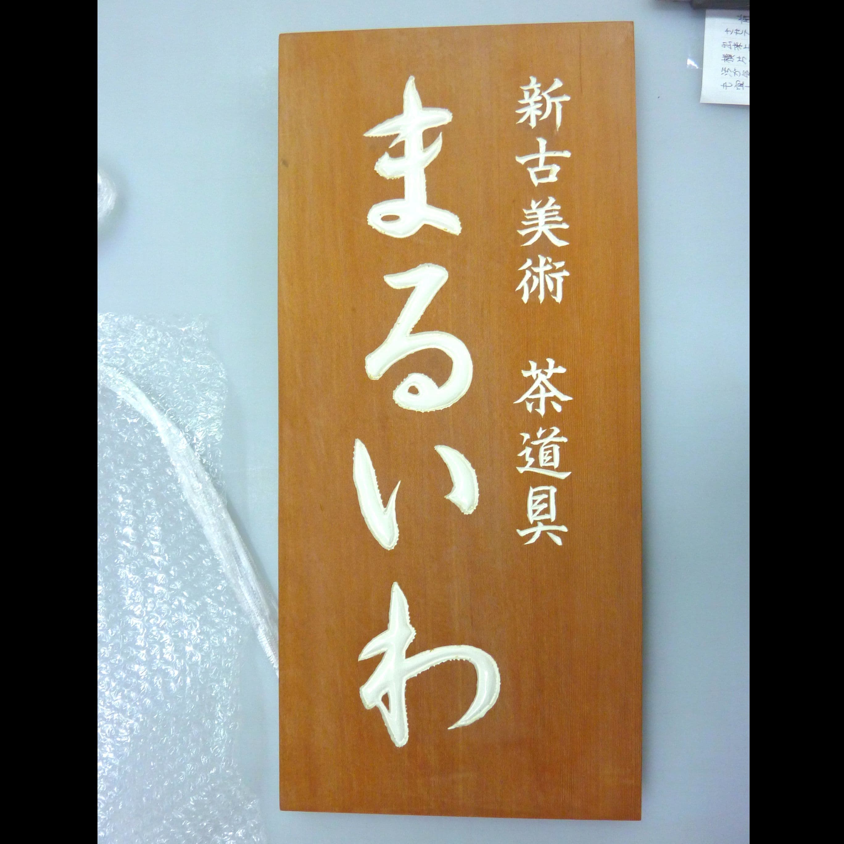 木の板に白い文字で屋号を彫刻した古美術商の看板